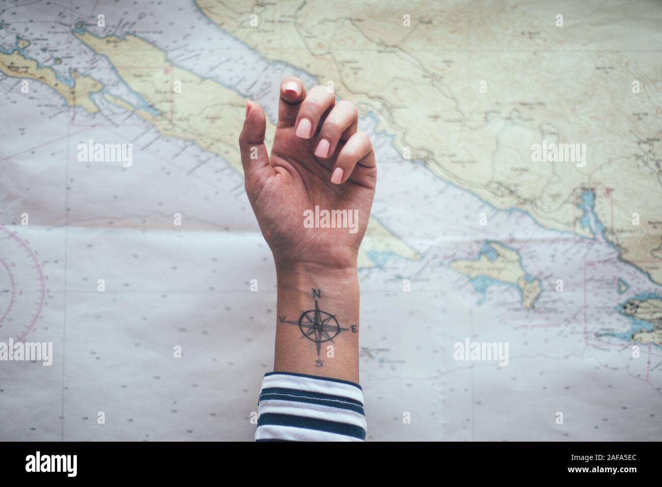Compass tattoo on sailor ankle with nautical chart in background Stock  Photo - Alamy