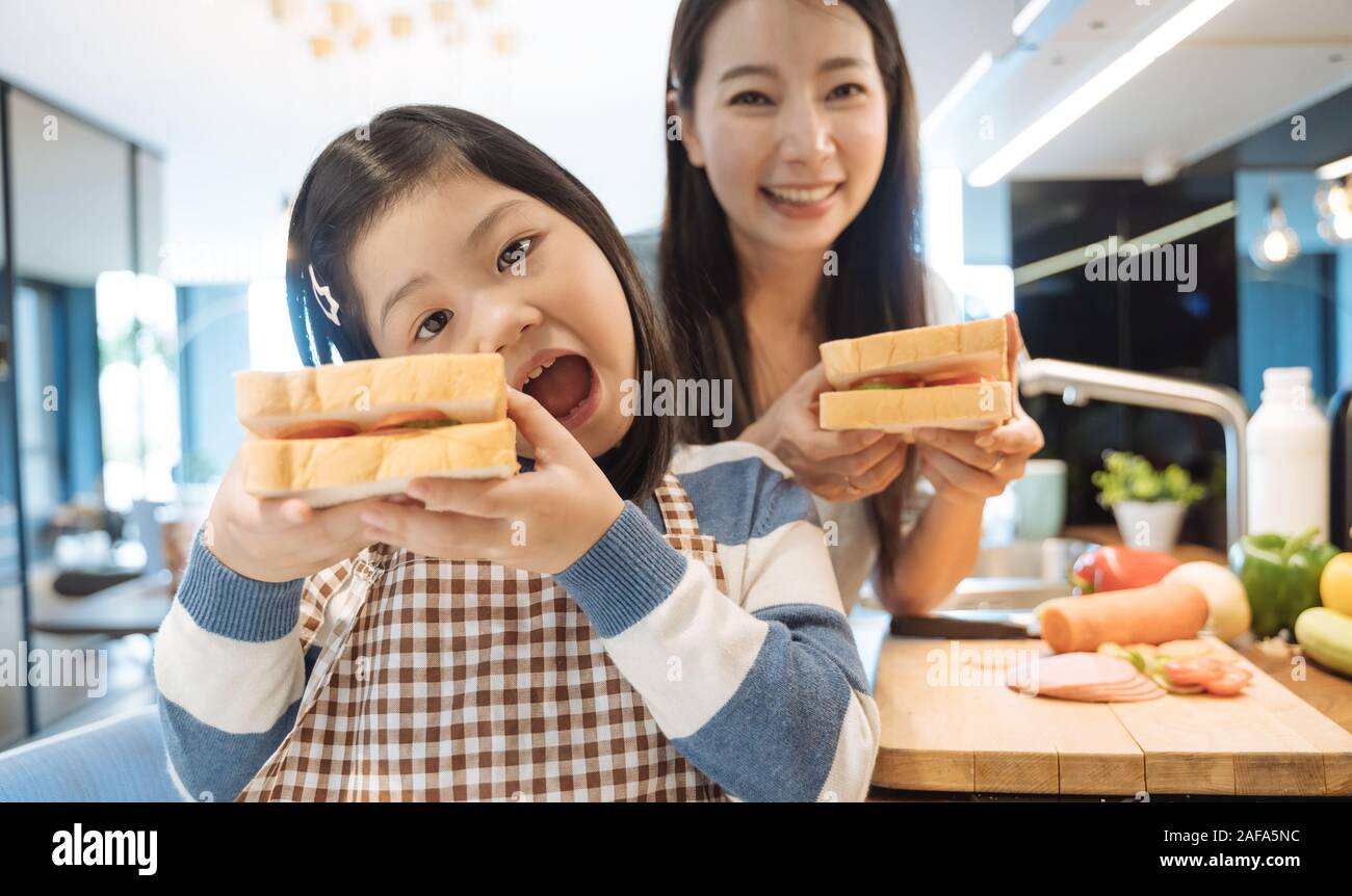 Daughter and mother preparing the sandwich and salad for breakfast in kitchen. Stock Photo