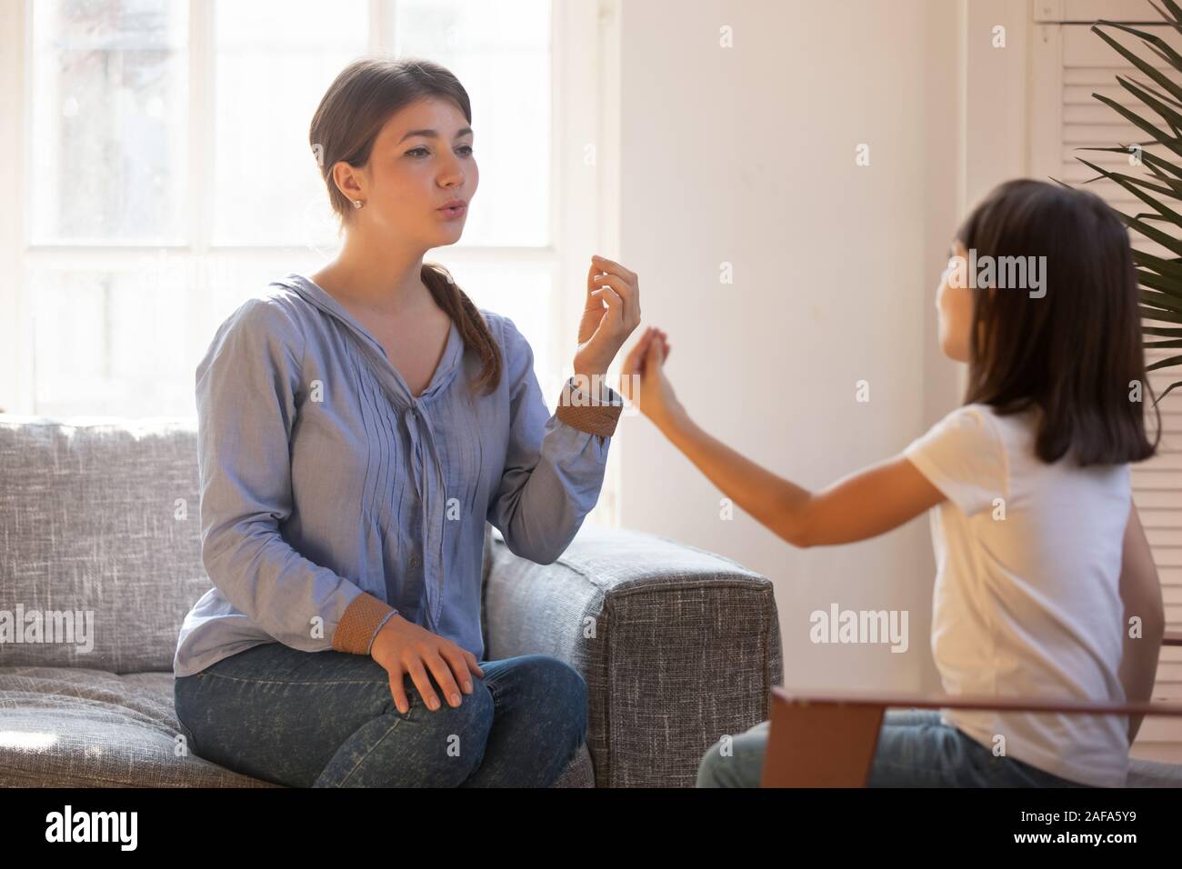 Female speech therapist doing exercise, speaking with little girl patient Stock Photo