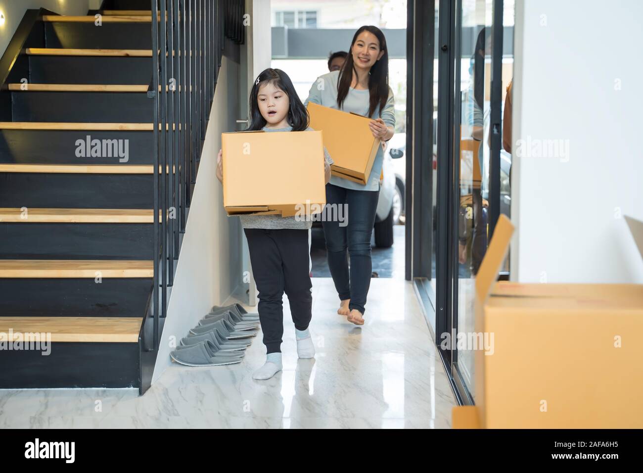 Portrait of happy Asian family moving to new house with cardboard boxes. Stock Photo