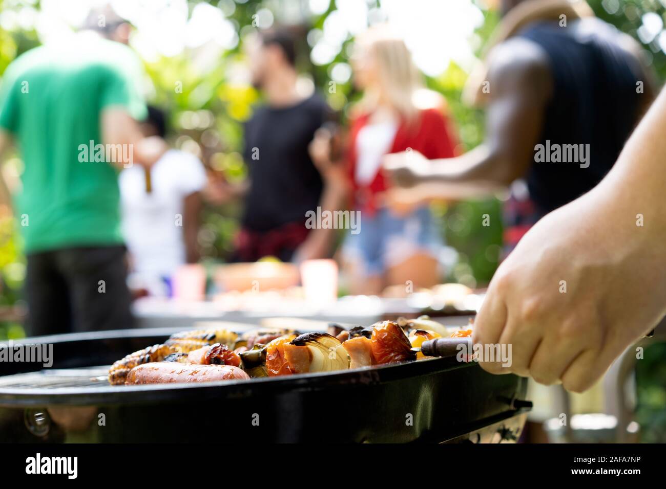 hand of bbq grilling and friends having barbecue party, outdoors Stock Photo
