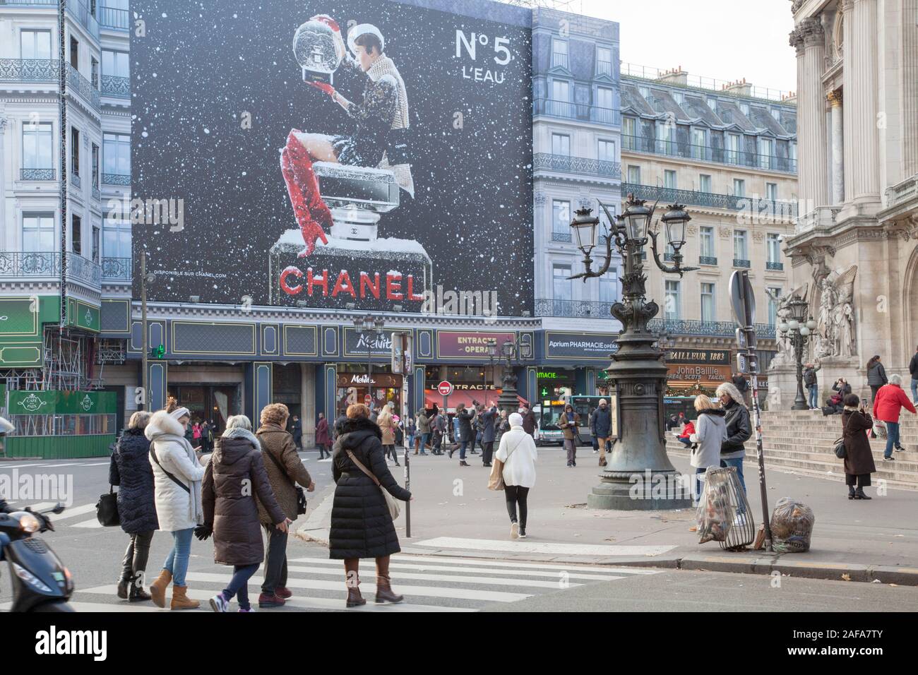 Pedestrians outside the Paris Opera building and a huge advert for Chanel No.5 perfume. Christmas 2019 Stock Photo