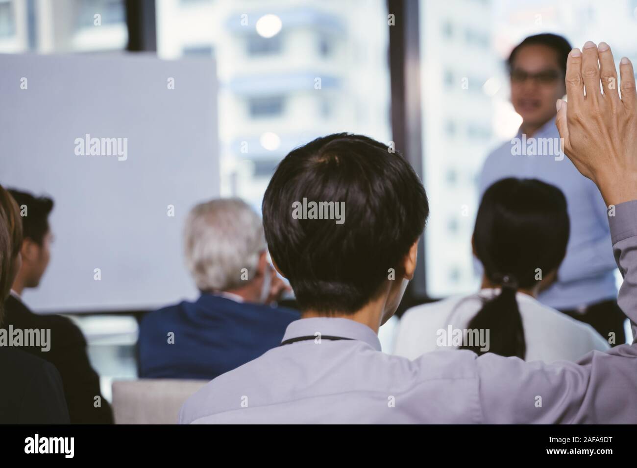 Raised up hands and arms of large group in seminar class room to agree with speaker at conference seminar meeting room Stock Photo