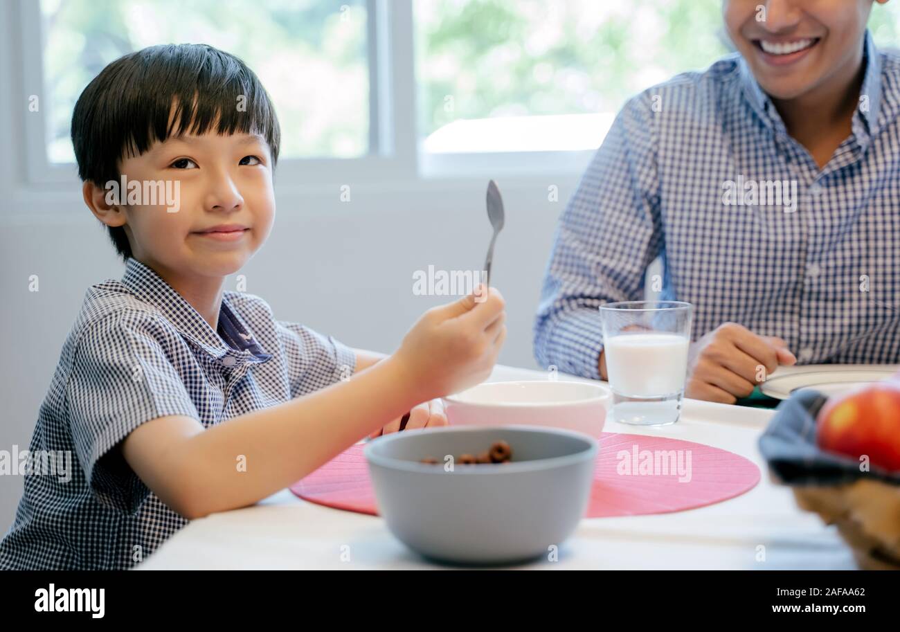The boy is having breakfast with his family at home. Stock Photo