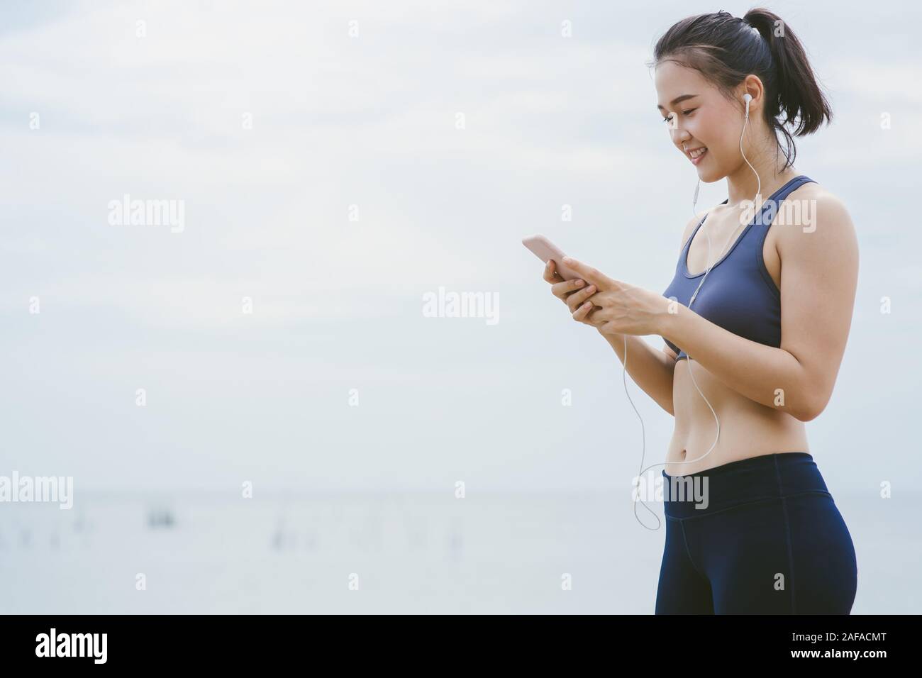 Young Asian Girl Choose Music for Running on the beach. Stock Photo