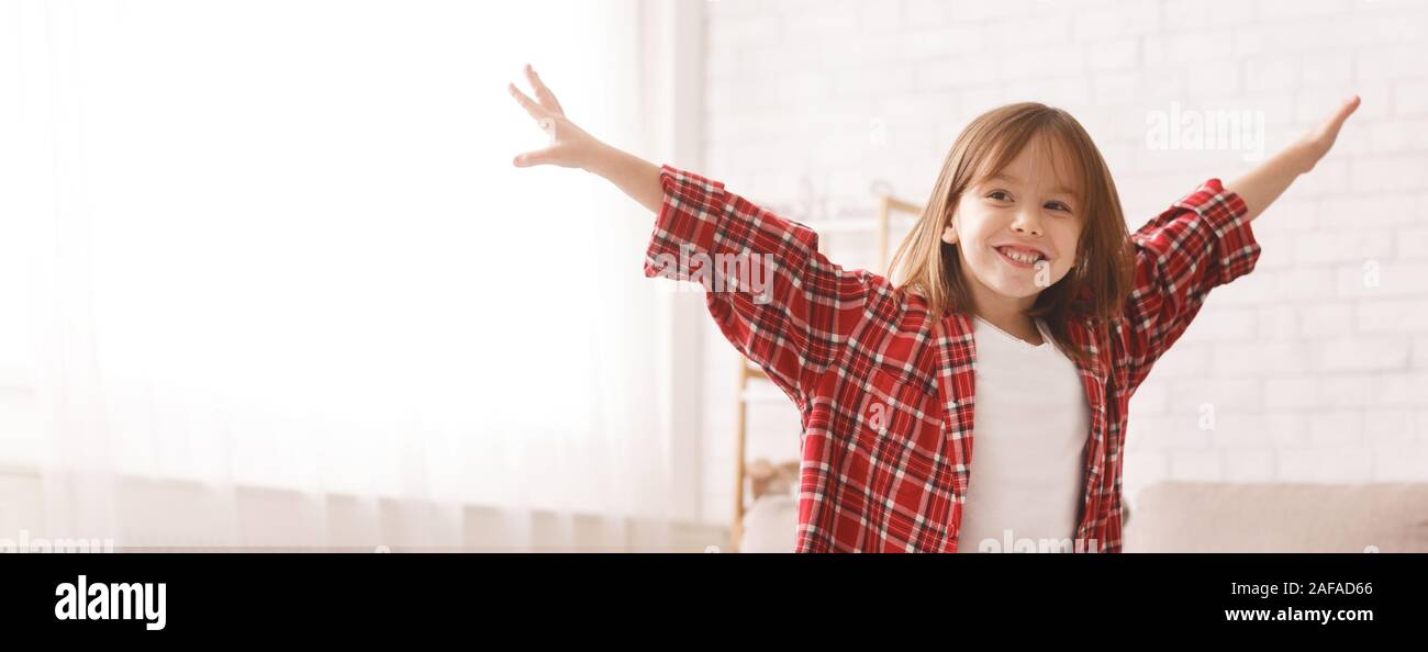 Smiling little girl raising hands up, having fun Stock Photo