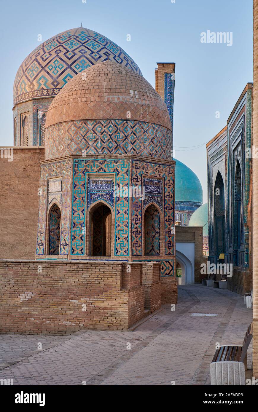 Shirin Biqa Aqa or Octagonal Mausoleum and narrow path through facades heavily decorated with blue tiles in necropolis Shah-i-Zinda, Samarqand, Uzbeki Stock Photo