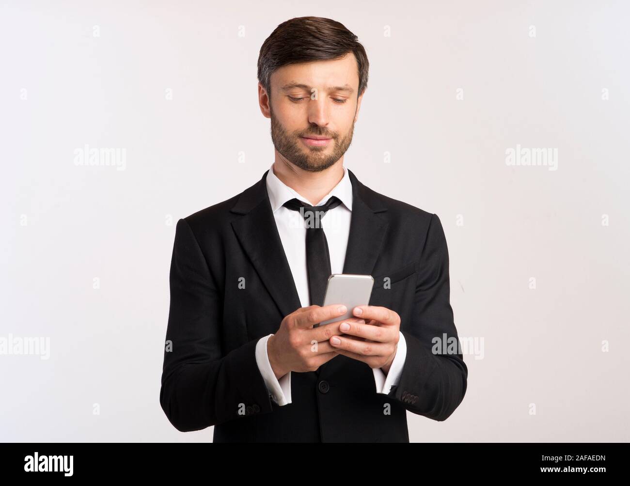 Man In Suit Using Phone Texting With Colleagues, White Background Stock Photo