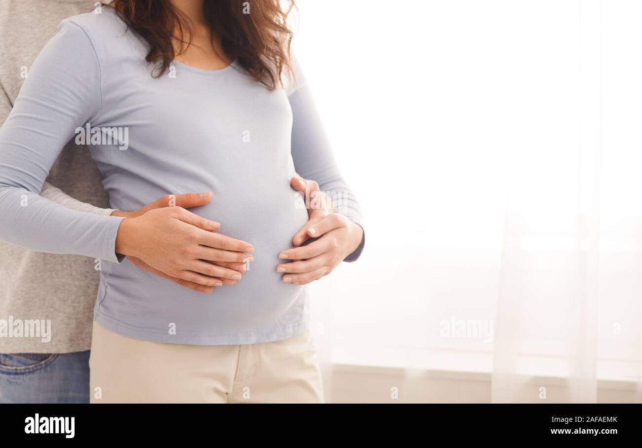 Loving husband tenderly touching his wife's belly Stock Photo
