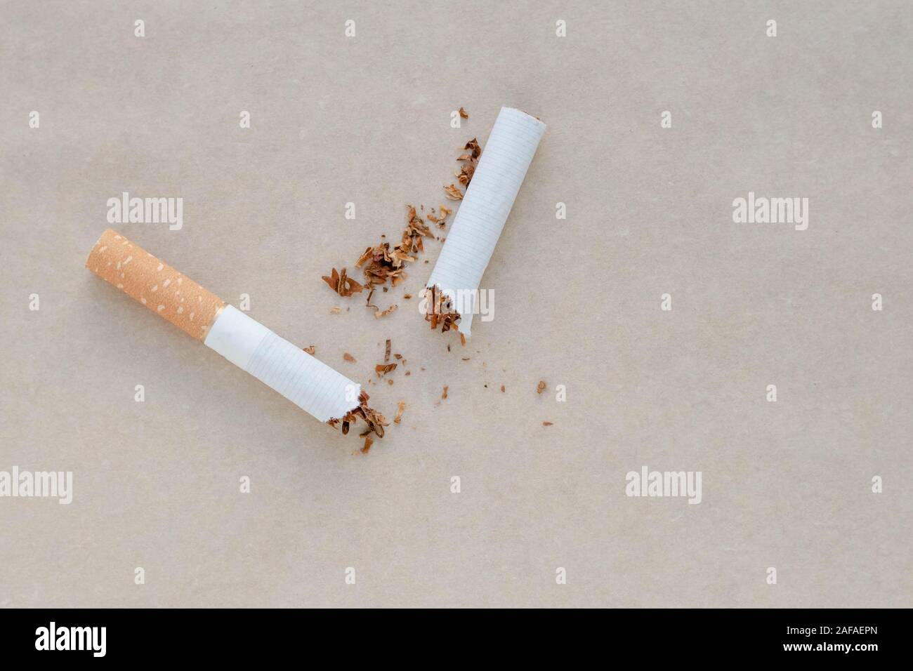 A broken cigarette on a light brown paper background. Scattered tobacco. Copy, text space. Bad habit. Say no to addiction. Healthy lifestyle concept Stock Photo