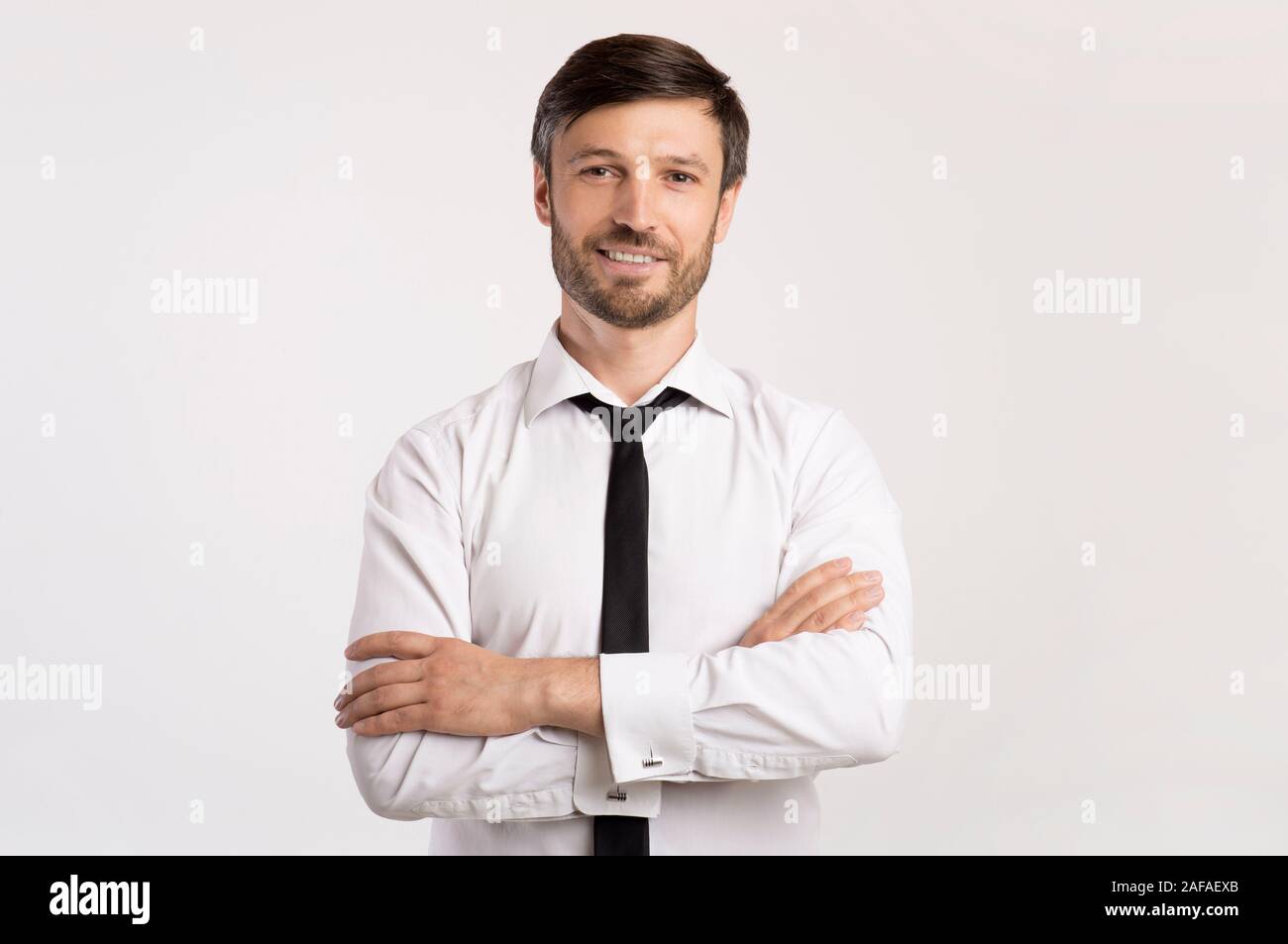 Positive Business Guy Smiling Crossing Hands Standing In Studio Stock Photo