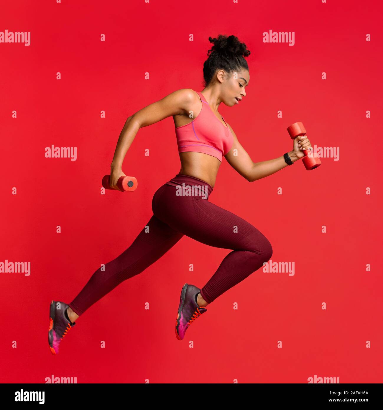 Active african woman training wth dumbbells over red background Stock Photo