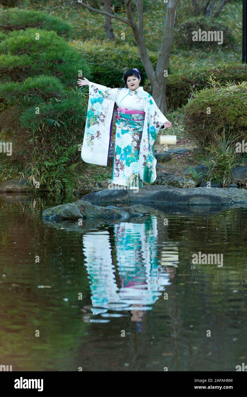 Beautiful Japanese teenager wearing traditional kimono standing looking forward with arms outstretched celebrating the Coming of Age Day in Fuji City, Stock Photo