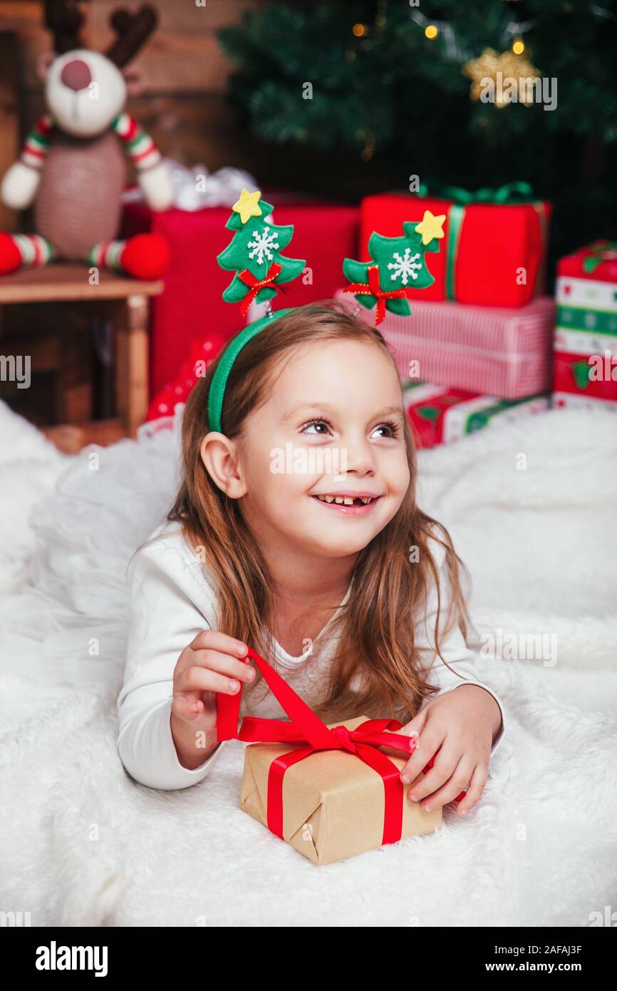 Happy little smiling girl with christmas gift box lying near Christmas ...