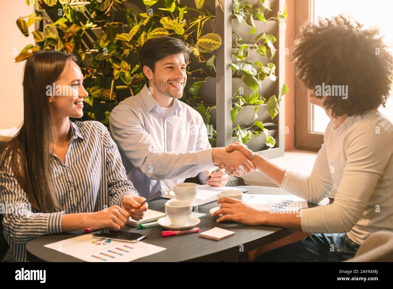 Cheerful partners handshaking in cafe, having agreement Stock Photo