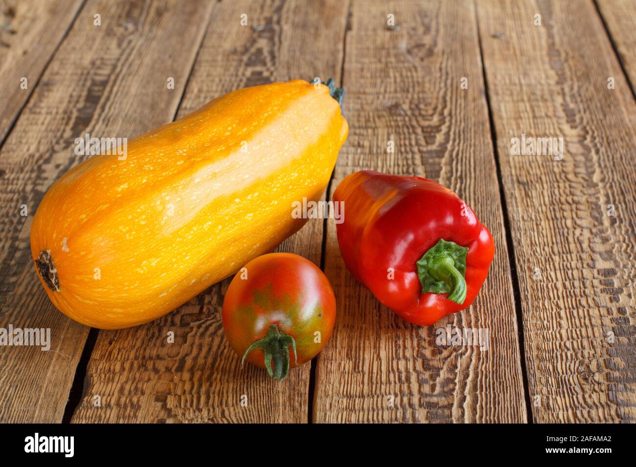 Just picked zucchini, tomato and red bell pepper on old wooden boards. Just harvested vegetables. Stock Photo