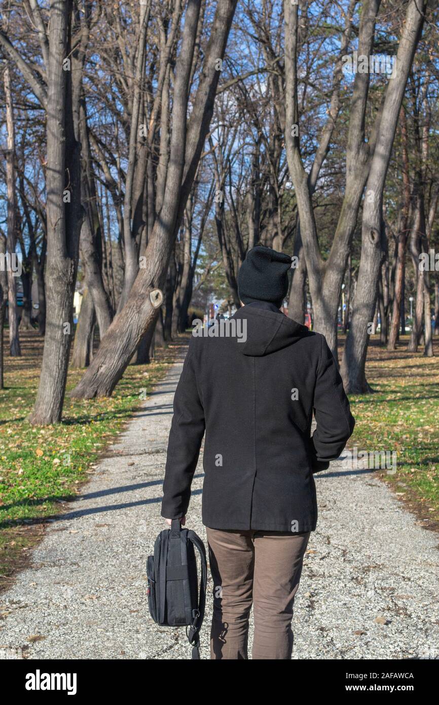 Young man walking away alone in a park in autumn Stock Photo