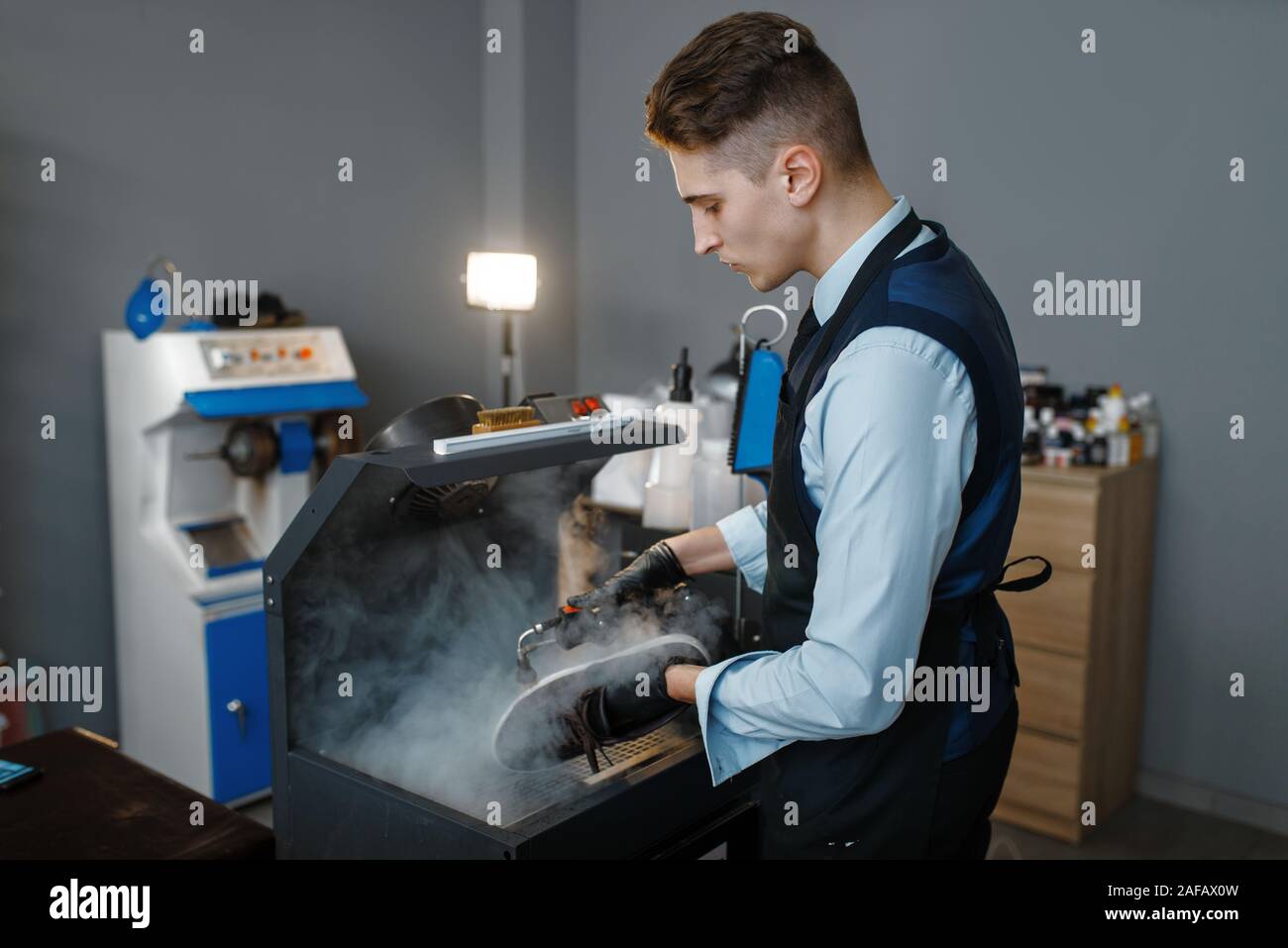Bootmaker processes the shoes on special machine Stock Photo - Alamy