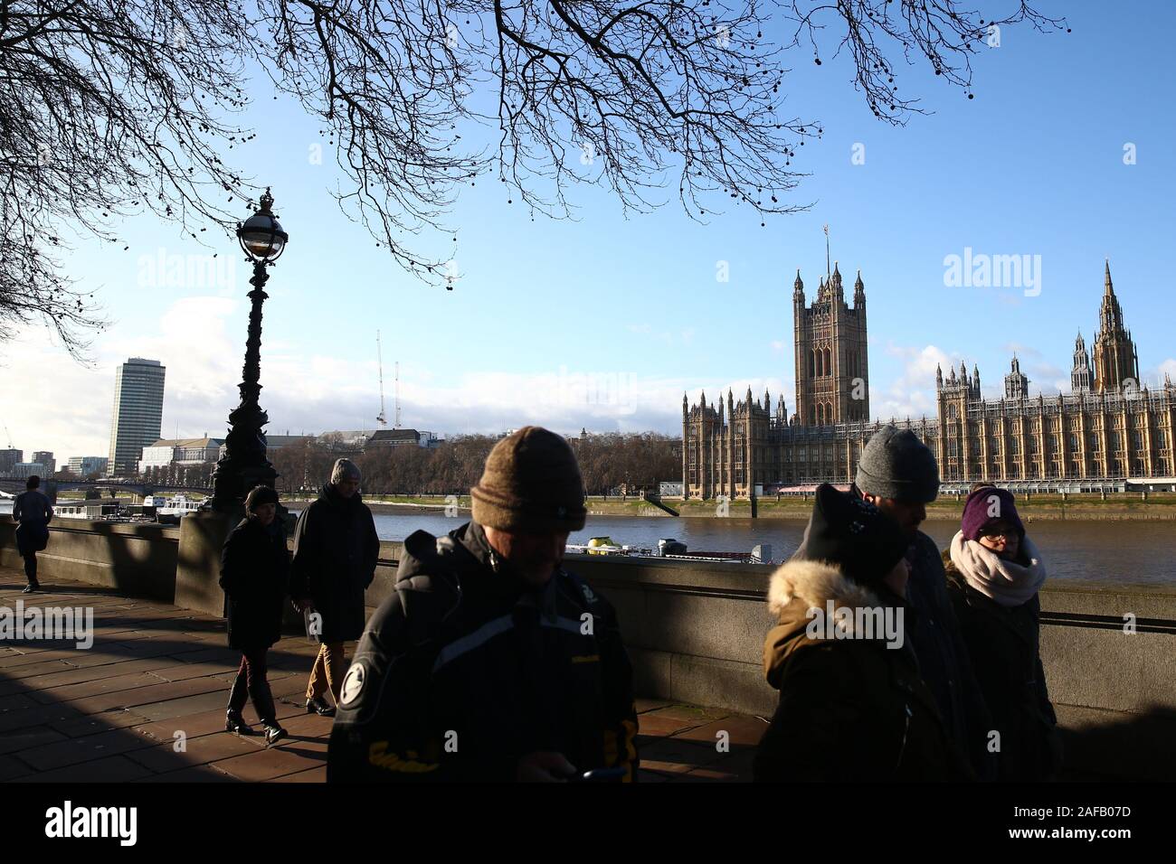 People walking along the Thames opposite the Houses of Parliament in London. Stock Photo