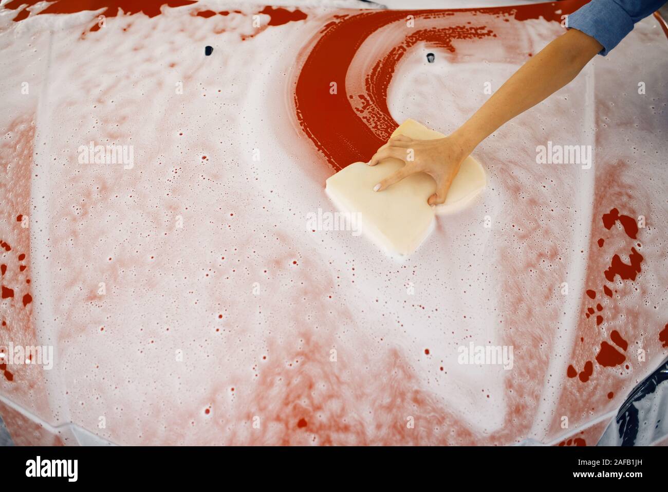 Female washer wipes the automobile hood, car wash Stock Photo