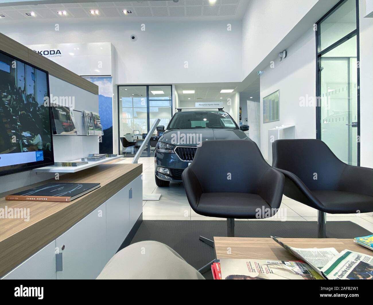 Paris, France - Oct 25, 2019: Interior of generic Skoda Car showroom with client waiting area with multiple magazines books and tv and car in background Stock Photo