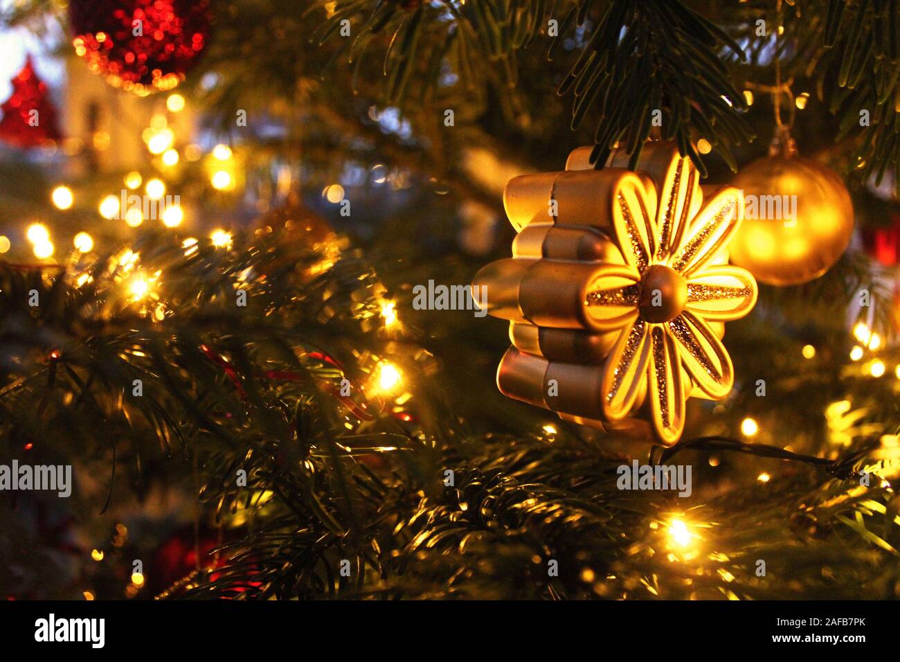 Gold flower Christmas ornament on a decorated Christmas tree Stock Photo