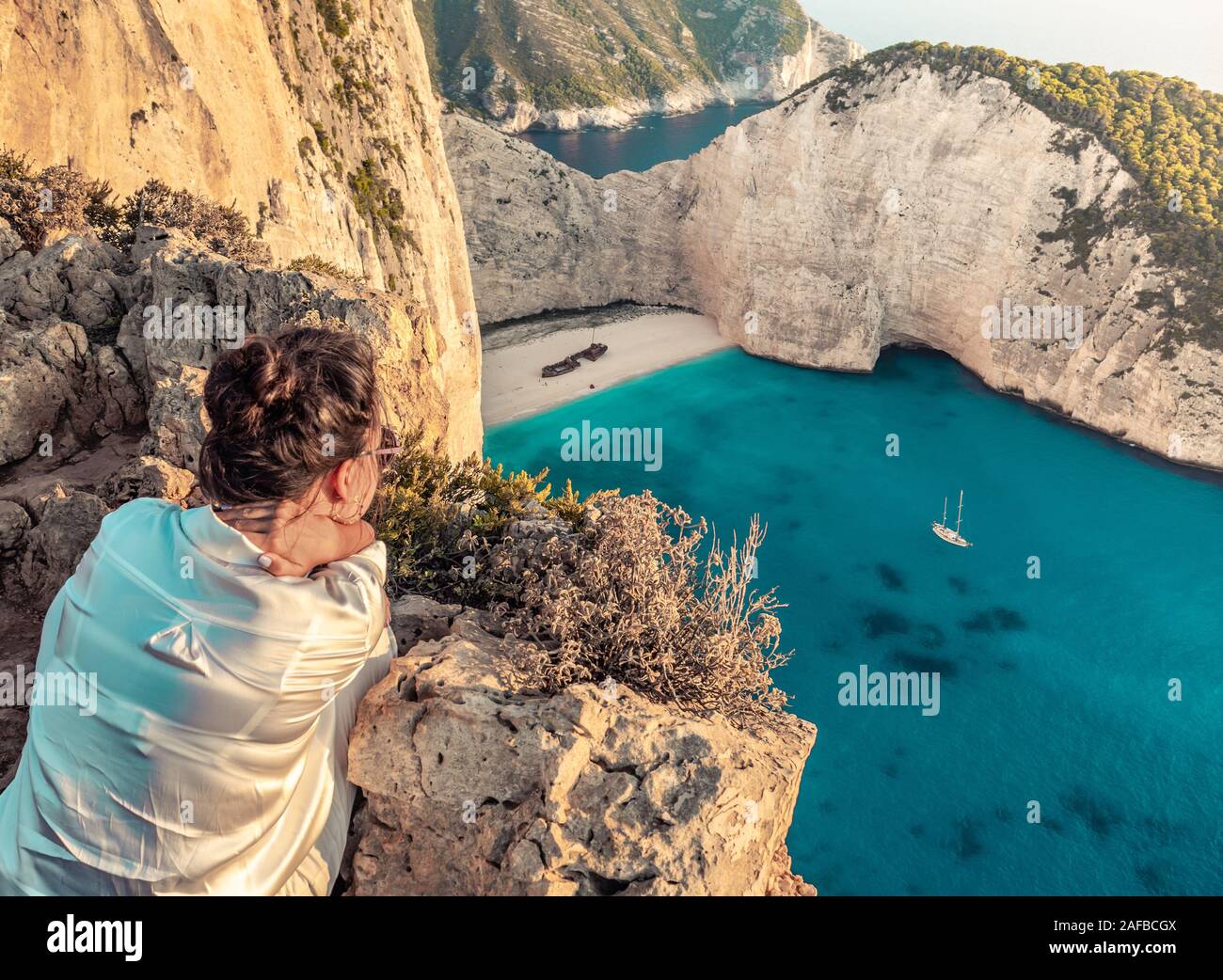 Young woman tourist looking at landscape in Zante - Zakynthos, Greece. Shiprweck Beach at sunset Stock Photo