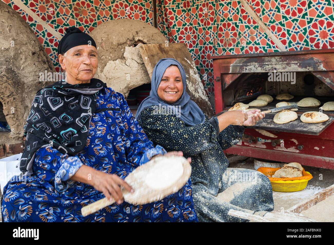 Africa, Egypt, Cairo. September 26, 2018. Two women baking traditonal AlShamsi bread in wood
