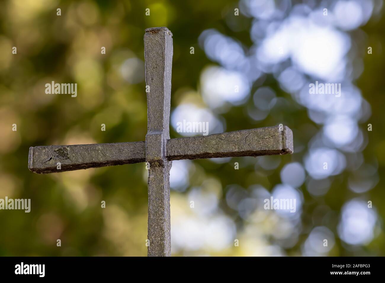 old weathered old christian cross in the back green and light-filled bubbles Stock Photo