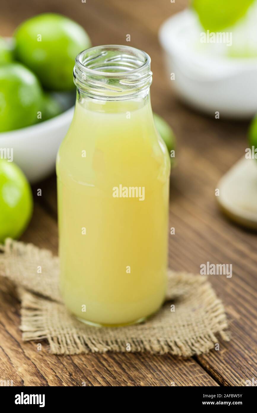 Fresh made Fresh Lime Juice on an old and rustic wooden table (selective focus, close-up shot) Stock Photo