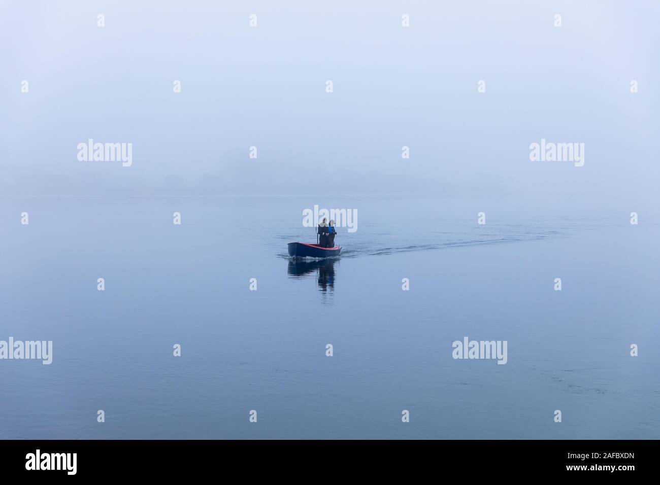 Two men in a small boat on Kerteminde Fjord, grey and foggy weather; Kerteminde, Denmark Stock Photo