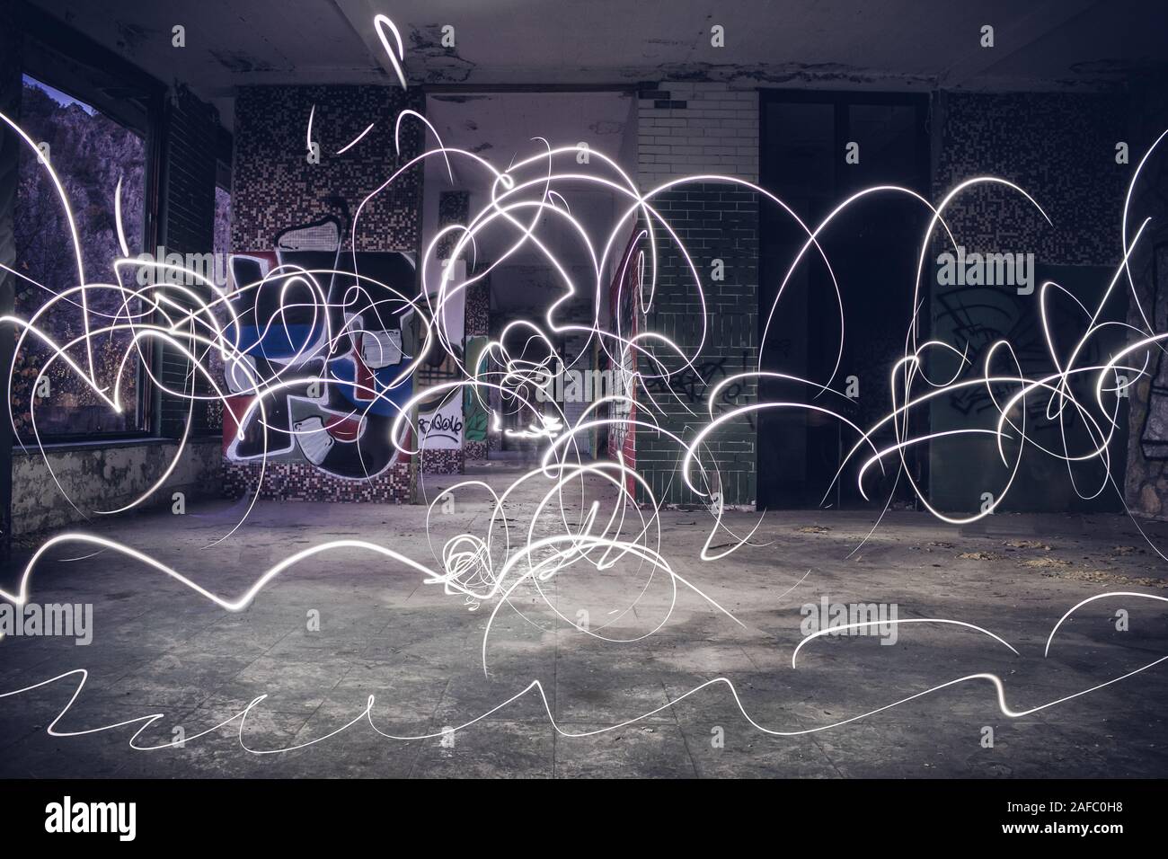 Light painting with smartphone led lamp in abandoned building. Long exposure shot, hectic chaotic light show. Stock Photo