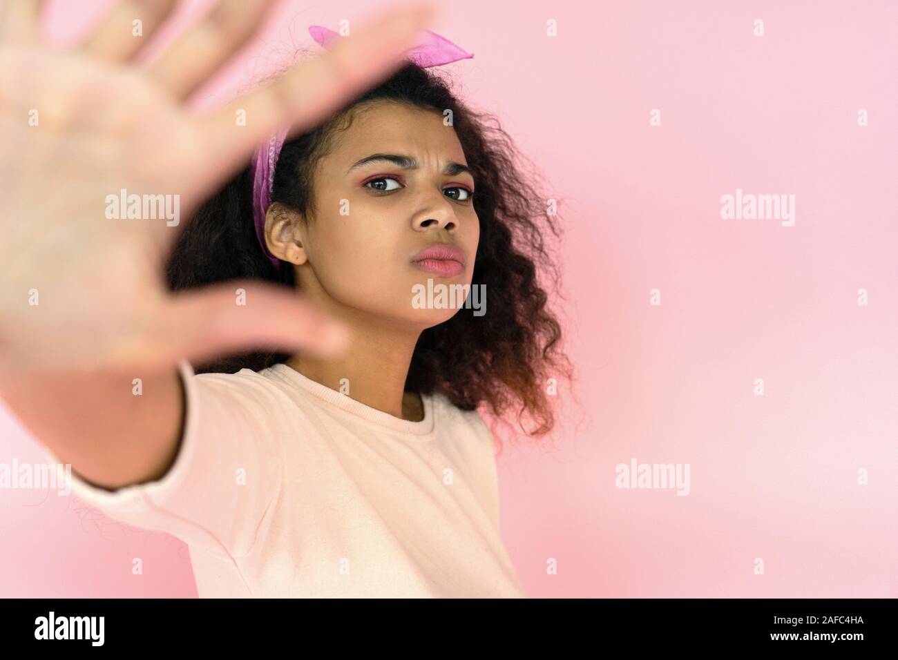 Annoyed african girl look at camera show stop hand gesture on pink background Stock Photo