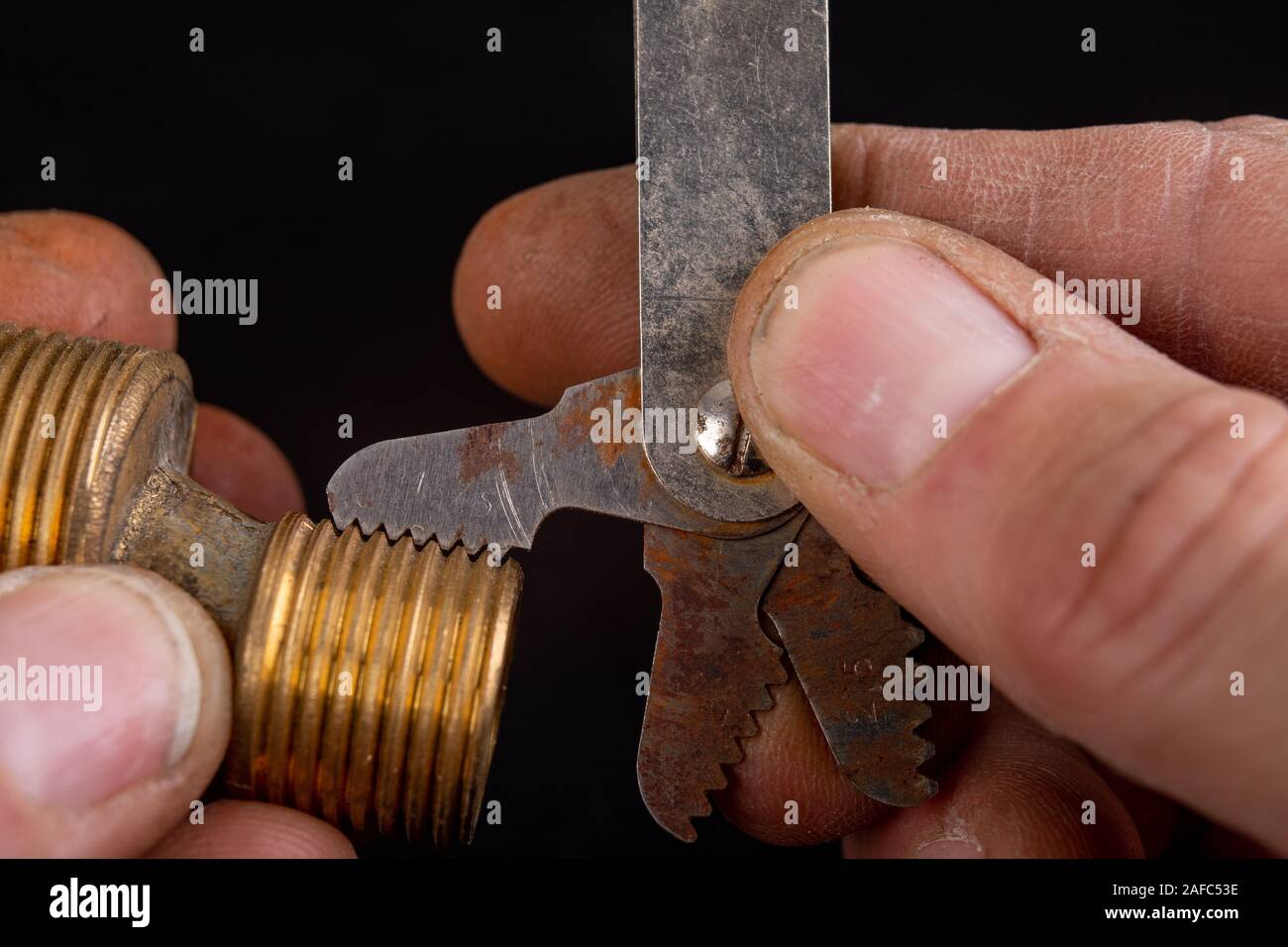 Checking the screw thread with an analog meter. Correctness of the threaded connection. Dark background. Stock Photo