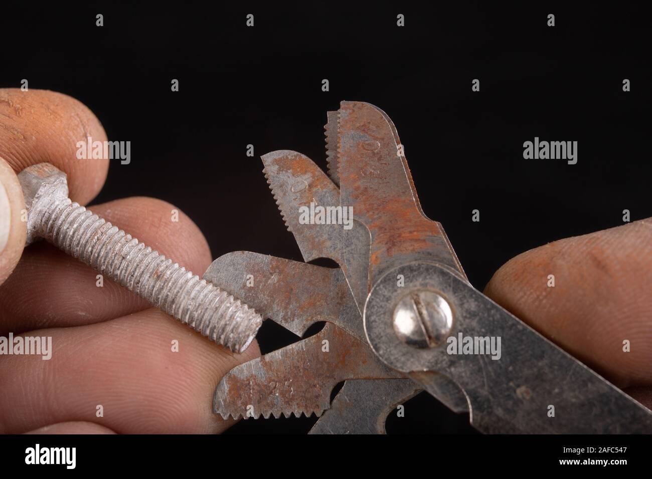 Checking the screw thread with an analog meter. Correctness of the threaded connection. Dark background. Stock Photo