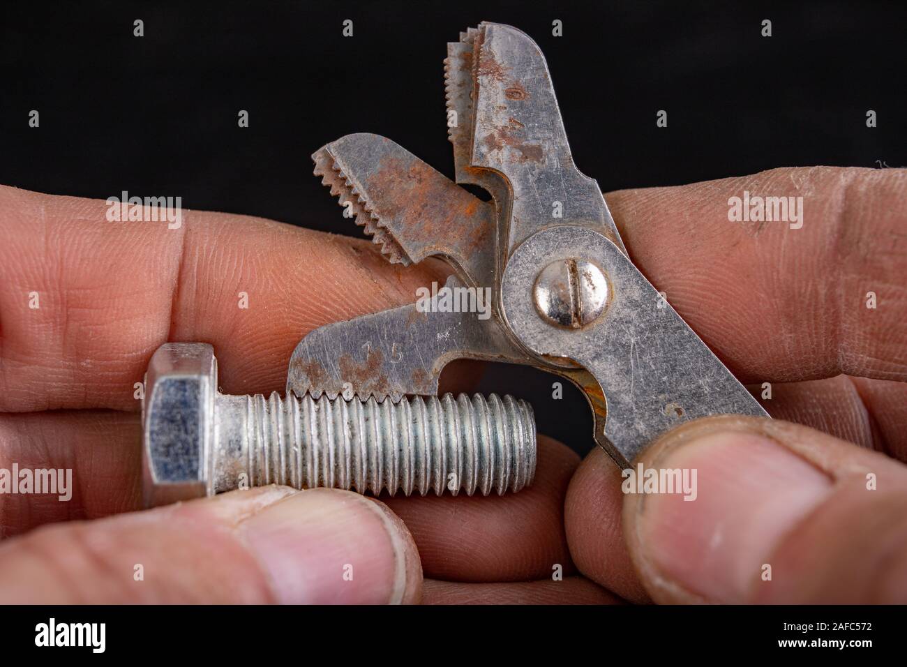 Checking the screw thread with an analog meter. Correctness of the threaded connection. Dark background. Stock Photo