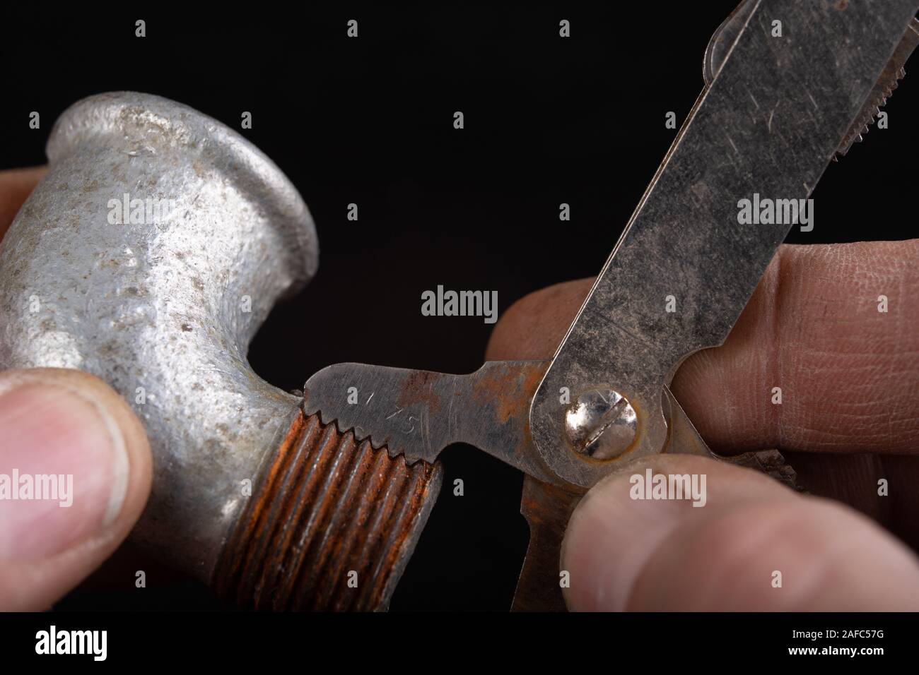 Checking the screw thread with an analog meter. Correctness of the threaded connection. Dark background. Stock Photo