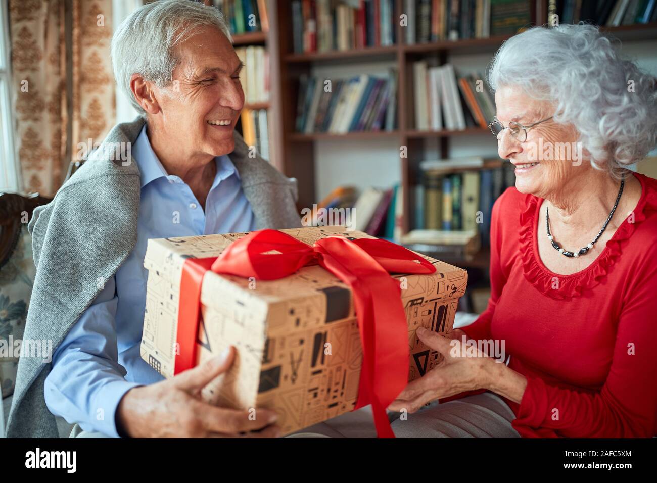 Loving husband giving a Christmas gift to his wife Stock Photo - Alamy
