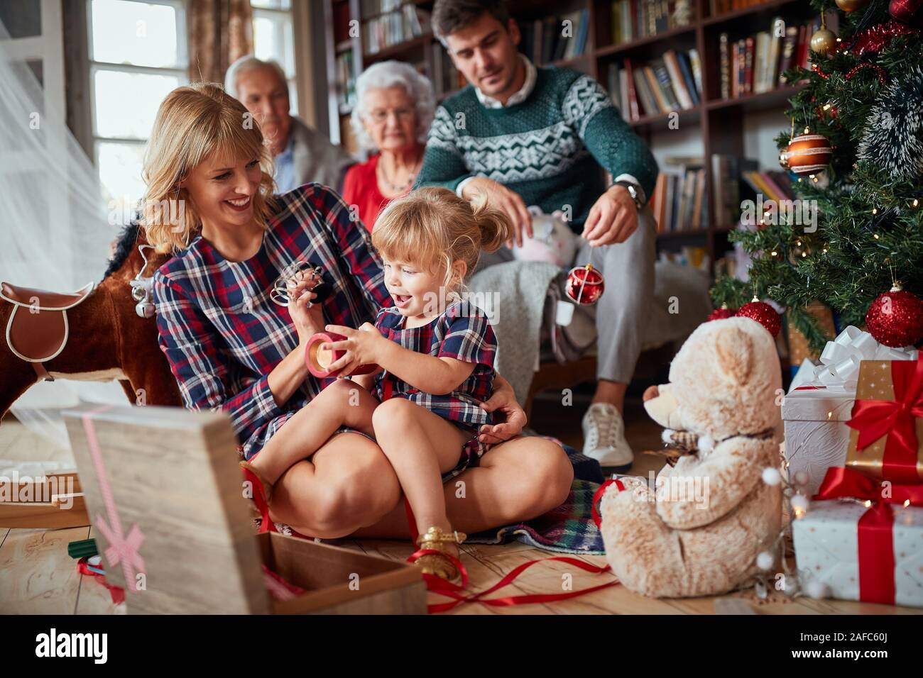 Caring mother teaching her child to decorate a Christmas tree, family