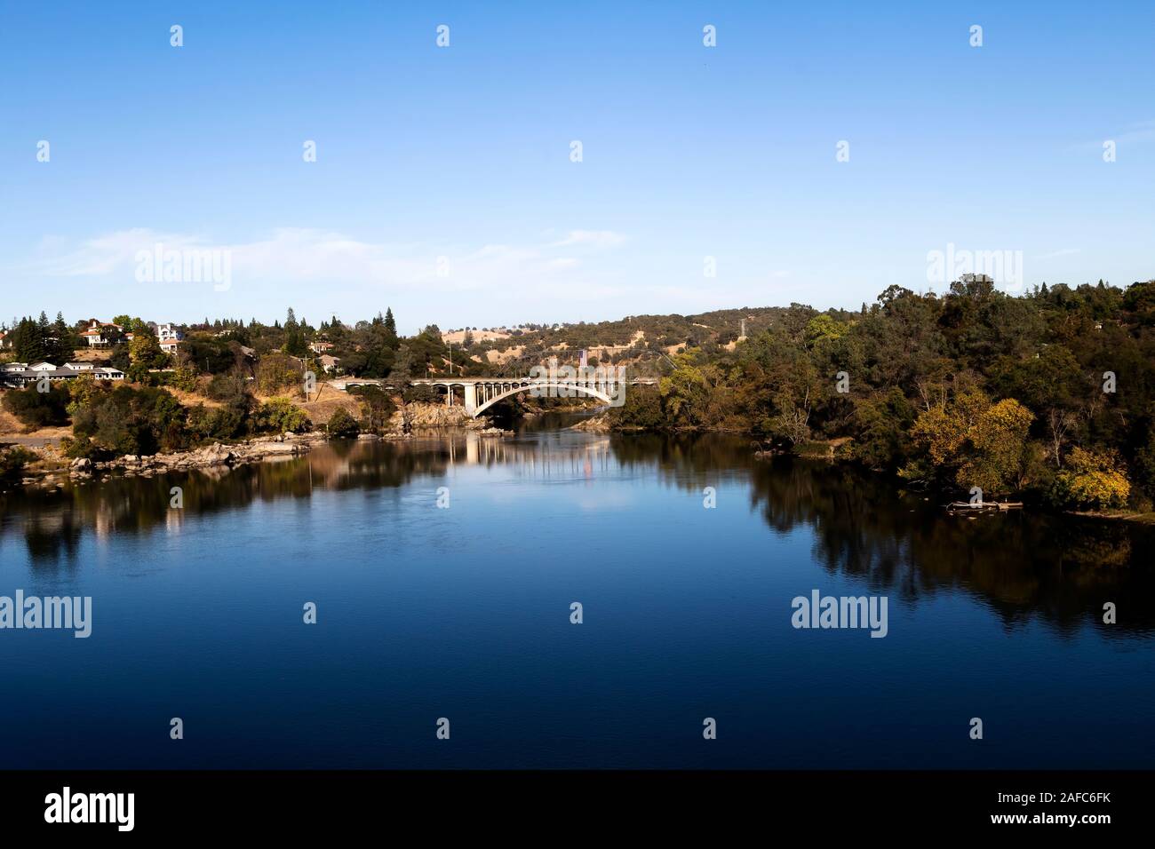 Blue Water And Sky Lake Natoma And Rainbow Bridge Folsom California With Trees Reflected In Water Stock Photo