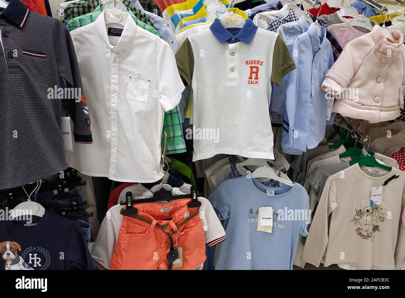 Clothes for children in a store close-up. Bright children's shirts and blouses on the shoulders in the children's goods store. Stock Photo