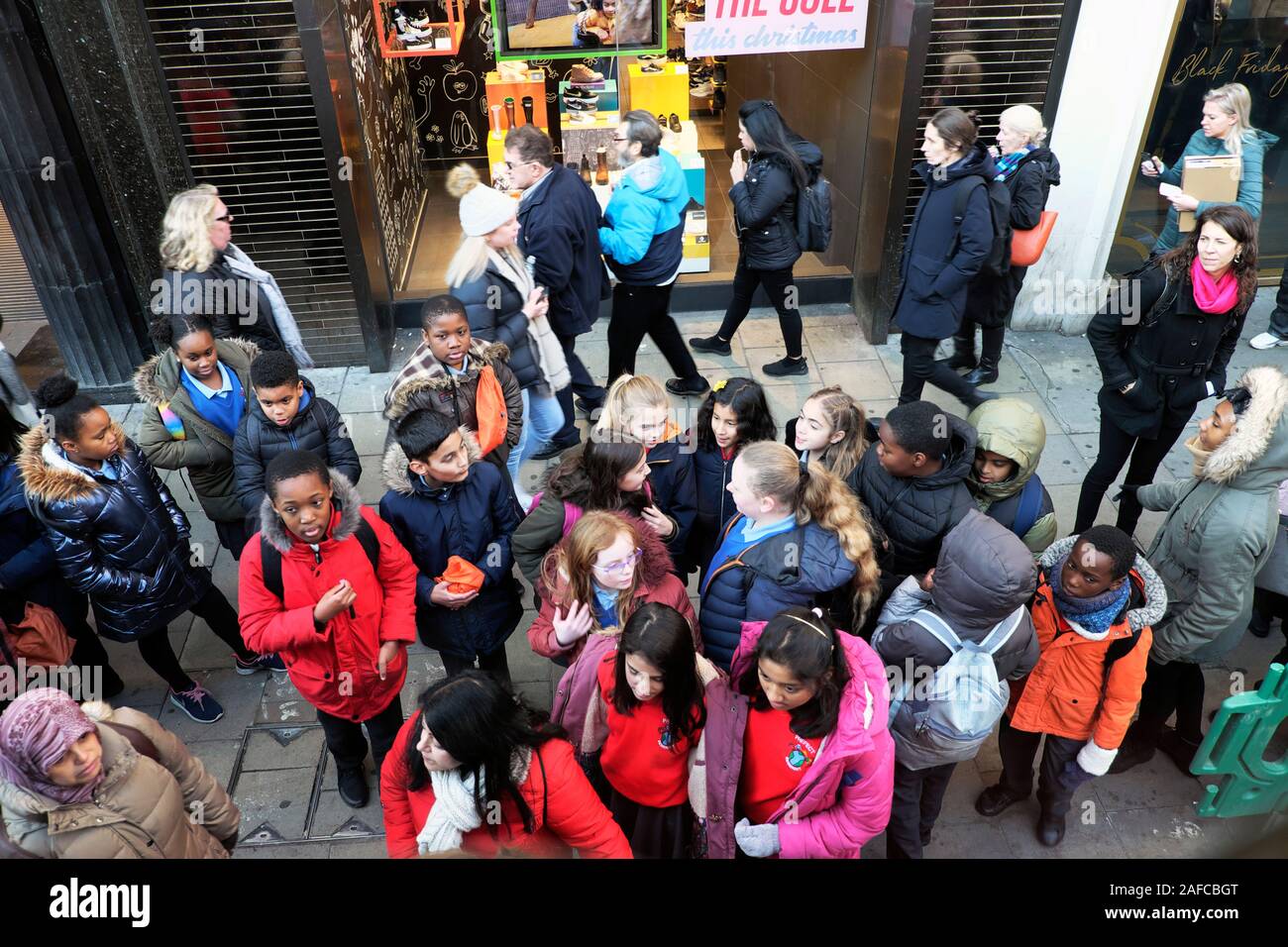 Group of school children waiting for a bus on a visit to Oxford Street in London England UK   KATHY DEWITT Stock Photo