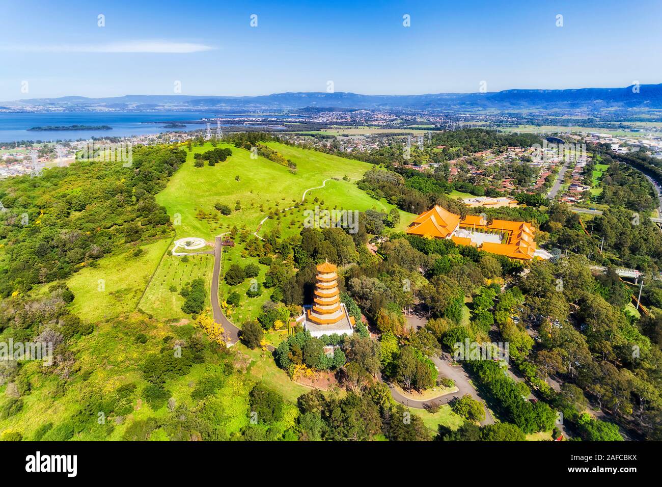 Distant Pacific ocean coast and Illawarra lake around green cultivated park of Nantien buddhist temple in Southern Hemisphere - Australian NSW. Aerial Stock Photo