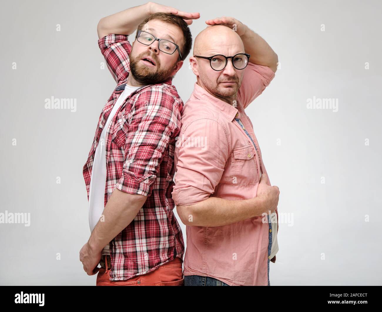 Men are measured by growth, they stood with their backs to each other as in childhood and are trying to determine who is taller. Stock Photo