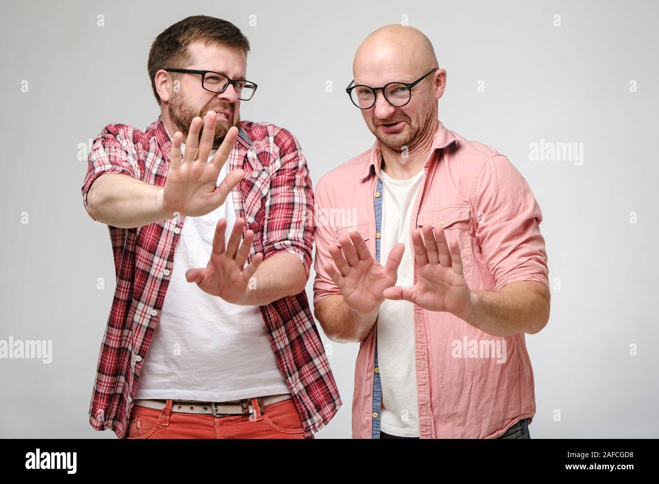 Friends look at the camera in disgust and defend themselves by making a gesture of palm forward. Negative emotions. Stock Photo