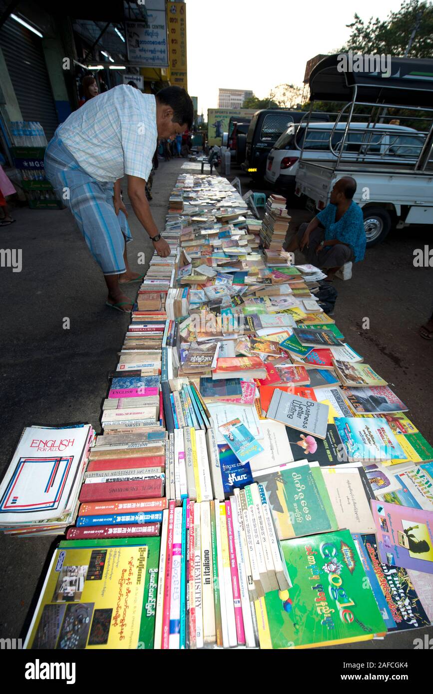 Outdoor book market with man bending over, Yangon, Myanmar Stock Photo