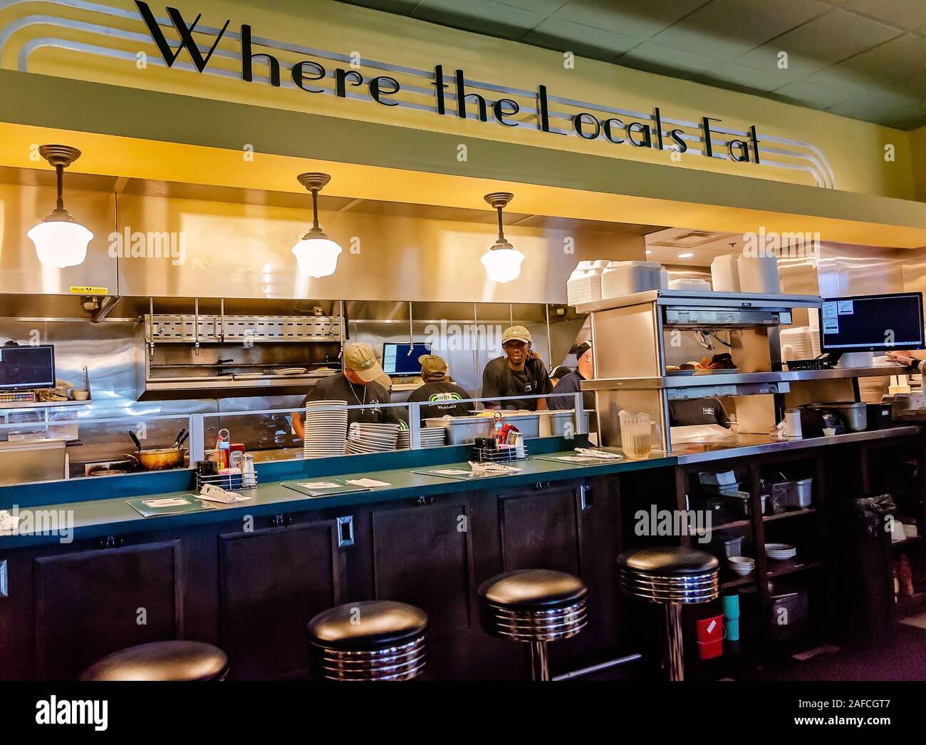 Cooks prepare food in the kitchen beneath a sign that states, “Where the locals eat,” at Metro Diner, July 29, 2018, in Huntsville, Alabama. Stock Photo