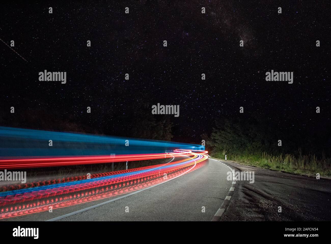 Photo of colorful car light trails and stars at night, long exposure. Stock Photo