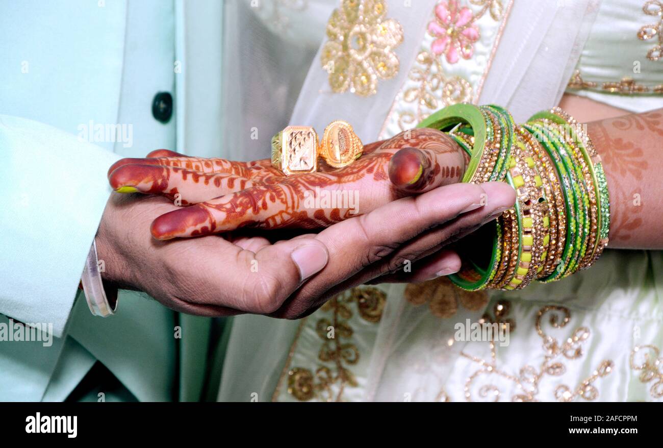 An Indian bride and groom holding their hands with ring during a Hindu wedding ritual Stock Photo