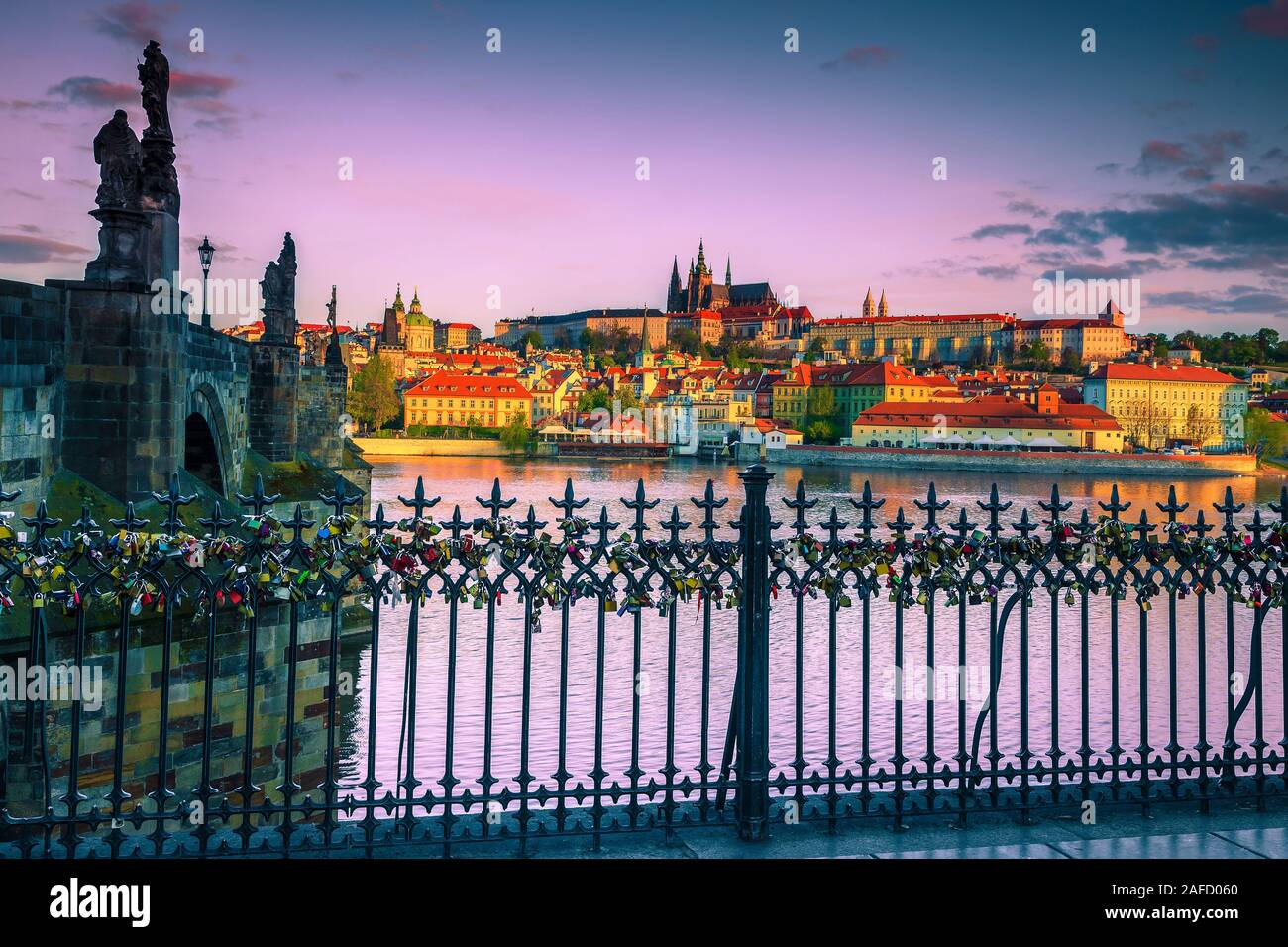 Wrought iron fence and railing decorated with romantic colorful padlocks. Well known buildings and locations at sunrise in Prague, Czech Republic, Eur Stock Photo